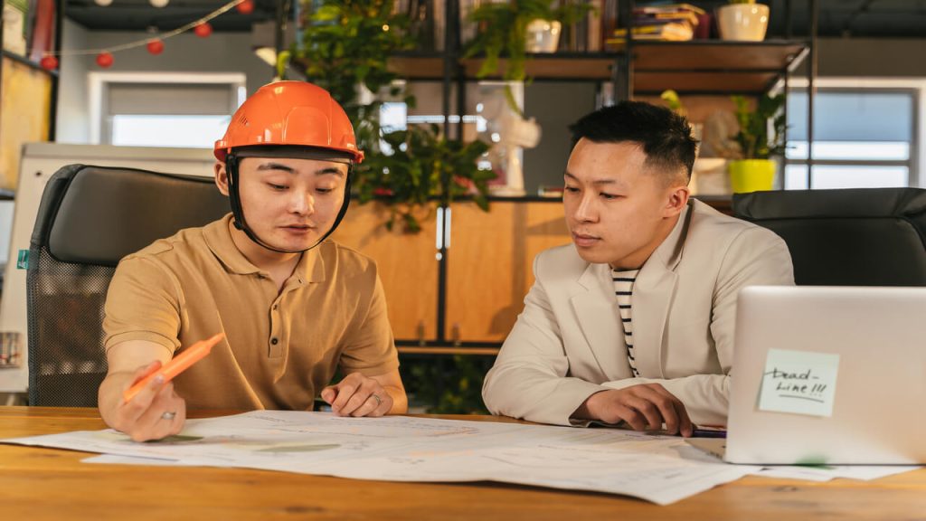 Construction manager and office worker reviewing plans in a modern office setting
